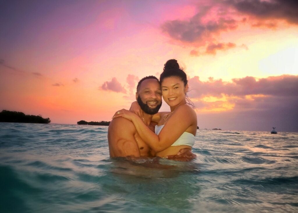 A honeymooning couple embraces in the crystal-clear turquoise waters of La Parguera's Cays, basking in the warmth of Puerto Rico’s vibrant sunset. This intimate and magical moment is part of Bucketlist Tours’ Mystic Waters Under the Sun & Stars experience, perfect for celebrating love and nature.