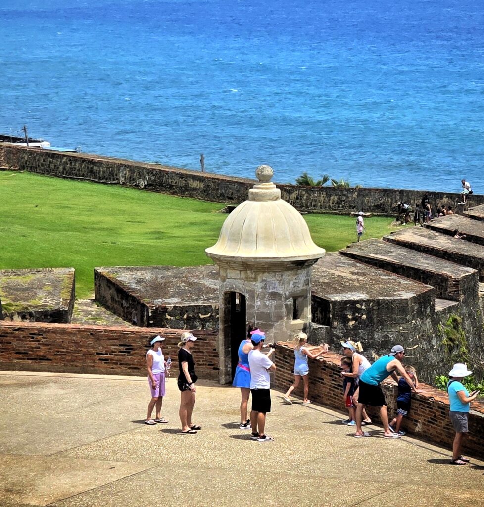 A family of twelve traveling to Puerto Rico and staying at the Fairmont El San Juan Hotel explores the historic walls near *San Cristobal Fort*. Captured by their guide amd ambassador during their Timeless Echoes & Legendary Spirits *Private Old San Juan Tour*, the family learns about Puerto Rico’s unique journey from a Spanish colony to becoming a *U.S. territory* and eventually a Commonwealth. They discover how Puerto Ricans gained *U.S. citizenship*, the island's critical role in World War II in defeating Nazi Germany and Japan, and its ongoing pursuit of equal rights and federal funding parity as *part of the United States*. This private tour combines a *Historic Old San Juan Tour* and a *Rum Distillery Tour*, offering an immersive experience that encompasses the entire San Juan Islet. Guests visit over 90 landmarks, including the Capitol Building, the *Walkway of the Presidents*, the North Wall, and the vibrant *cobblestone streets of Old San Juan*. Tailored for safety and comfort, this experience is ideal for couples, families with children, seniors, individuals with *mobility constraints*, and cruise ship passengers seeking a low-effort, enriching exploration.