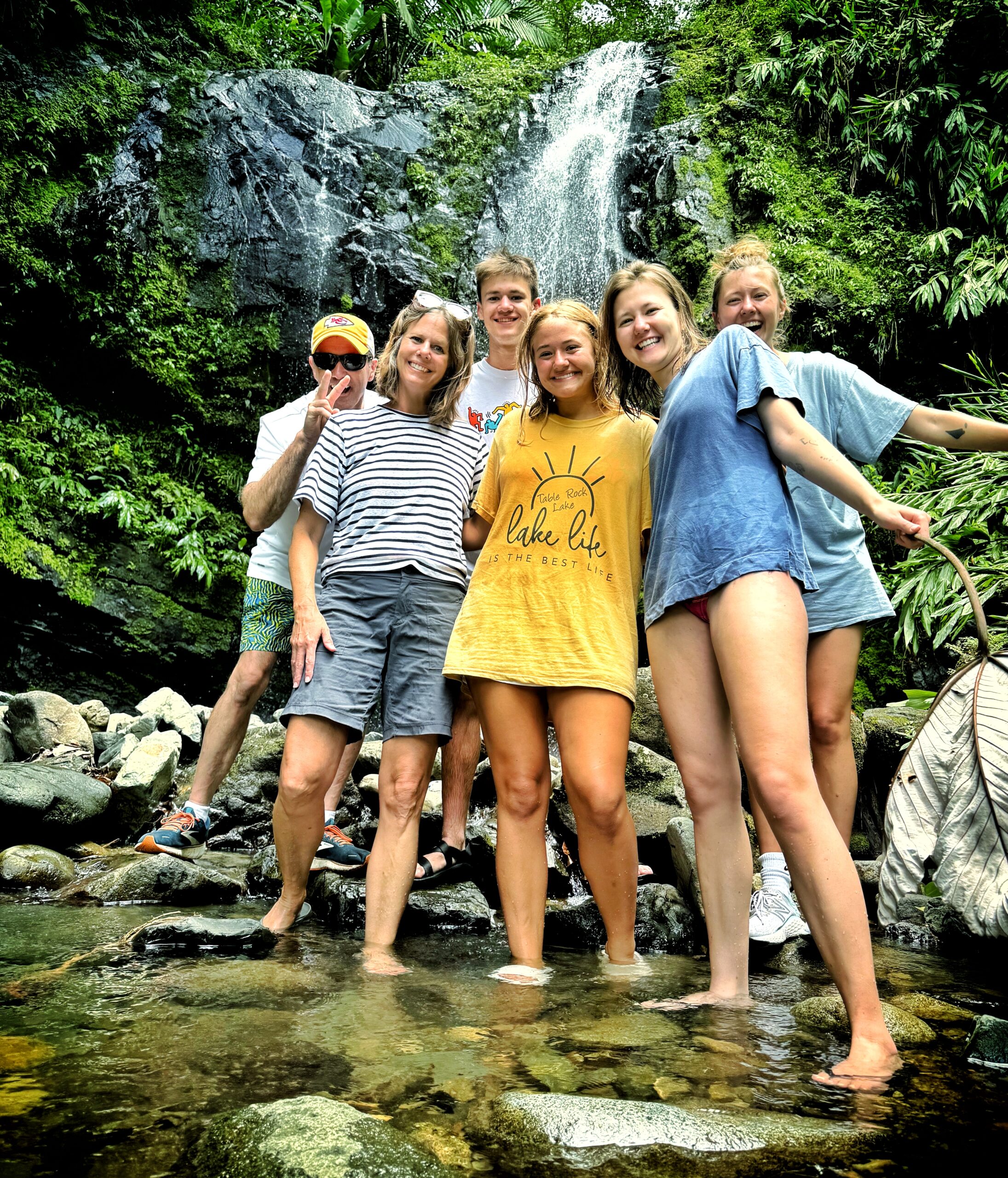 A Christian family enjoying a fun-filled day and making playful poses in front of the majestic Las Delicias Waterfalls at Toro Negro Rainforest. This unique adventure is a highlight of Bucketlist Tours’ Ocean Edge to Jungle’s Heart private experience, designed for memorable family moments and accessible from San Juan, Dorado, and Rio Grande.