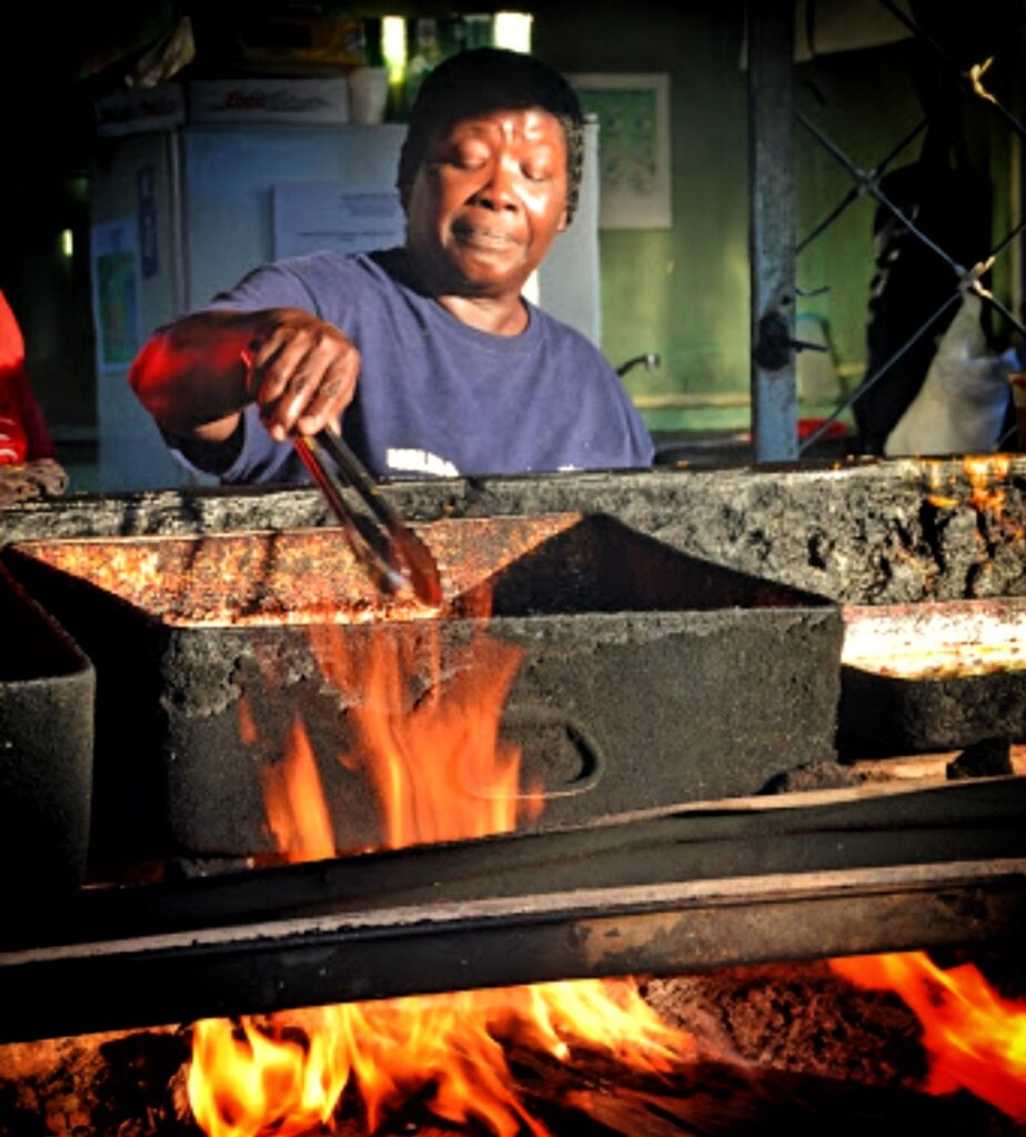 A local African descendant woman from Piñones, Puerto Rico’s African heritage hub, tends to a sizzling wood fire as she cooks authentic African-Taino fusion dishes using time-honored techniques. Her dedication reflects the deep cultural and historical roots of this vibrant community. Guests on Bucketlist Tours’ Colonial Spaniard Splendor and African Spirit Private Old San Juan Tour witness and savor these traditions firsthand, connecting with Puerto Rico’s rich heritage.