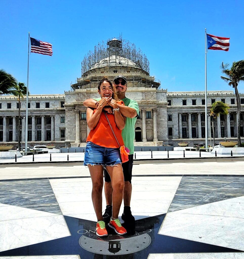 A young Latino couple, traveling aboard the Ritz Carlton Cruise Ship *Evrima*, poses in front of *Puerto Rico's State Capitol* during their private Timeless Echoes and Legendary Spirits Captured by their guide and ambassador, the couple learns about Puerto Rico's transition from a territory to a commonwealth, the granting of *U.S. citizenship to Puerto Ricans*, and their ongoing quest for equal rights and parity in government funding with the 50 states. The comprehensive tour explores the San Juan islet, covering over 90 landmarks, including the Capitol Building, the *Walkway of the Presidents* (honoring U.S. presidents who visited the island while in office), the northern walls, and the main streets of the historic city. Offered in three lengths—2 hours for a comfortable sightseeing tour in a luxury air-conditioned vehicle, 3 hours with 2–3 stops for photos and exploration, or 4 hours with 4 extended stops—the experience is designed with safety, comfort, and accessibility in mind, catering to couples, families, seniors, individuals with *mobility constraints and cruise ship passengers.