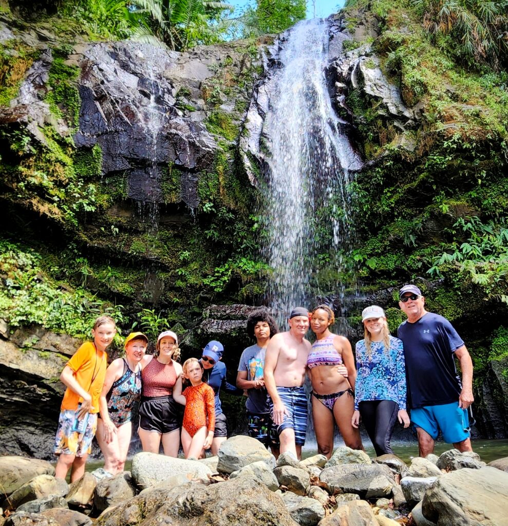 A family with children and seniors happily poses for their guide and ambassador after enjoying a refreshing dip at Toro Negro's Tropical Rainforest Las Delicias Waterfall. This memorable moment is part of their Tropical Rainforest Magic and Wonders Private Tour, offered from San Juan, Dorado, and Rio Grande. Designed for travelers aged 2 to 85, this private, tailored experience provides exclusive access to hidden, off-the-beaten-path gems, ensuring both fun and safety for all participants. The family enjoyed the comfort of luxury private transportation throughout their adventure.