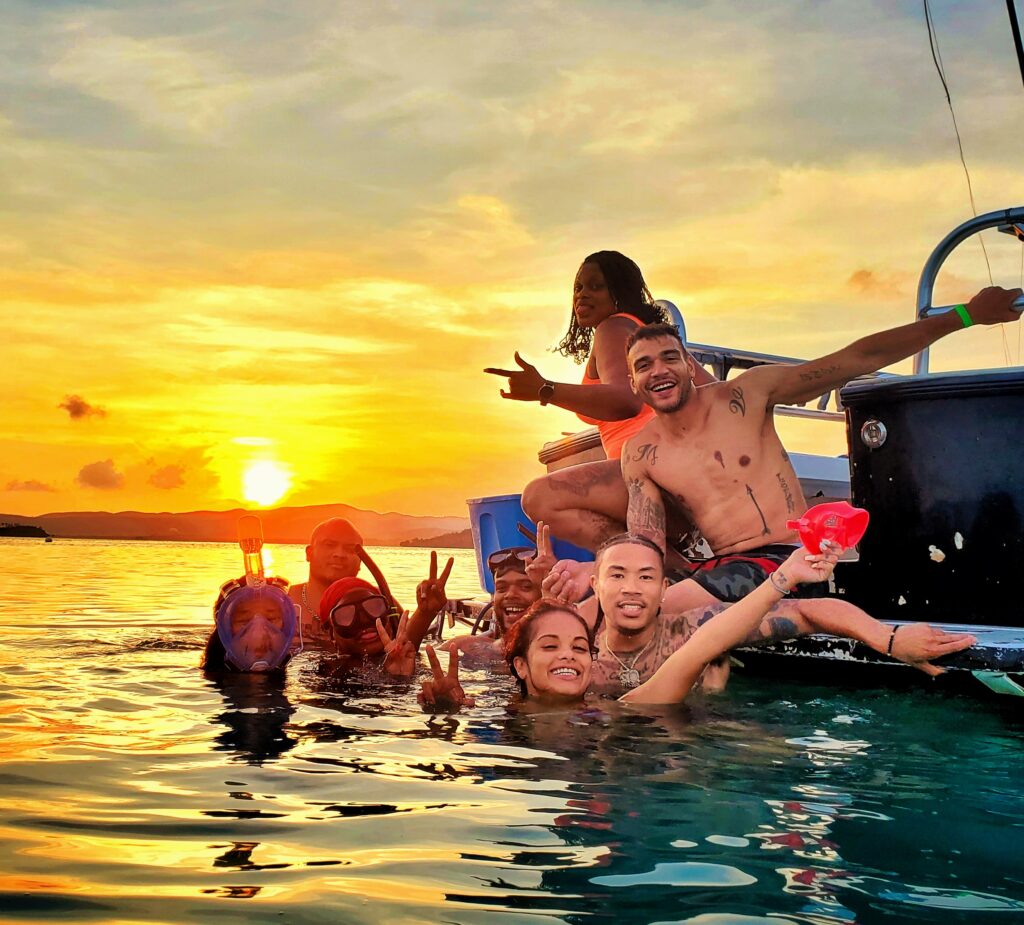 A group of young crypto investors, enjoying their stay at the luxurious Ritz-Carlton Reserve at Dorado Beach, capture a vibrant memory while immersed in the warm and clear waters of La Parguera. With the Caribbean sunset painting the sky in hues of gold and orange, this magical experience is part of Bucketlist Tours' Mystic Waters under the Sun & Stars and Discover Puerto Rico 3-Day Package Private Door to Door Experiences.