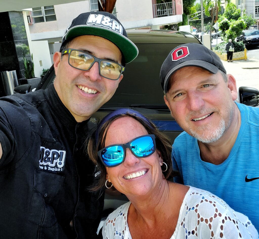 A couple traveling to Puerto Rico and staying at Condado Vanderbilt shares a happy selfie with Carlos Alexis, AKA Papito, their guide and Bucketlist Tours Ambassador, after an incredible day Puerto Rico's beaches in the Northern Coastal Adventure. Their radiant smiles capture the joy and unforgettable memories created during their personalized tour. Moments like these showcase the unique experiences Bucket