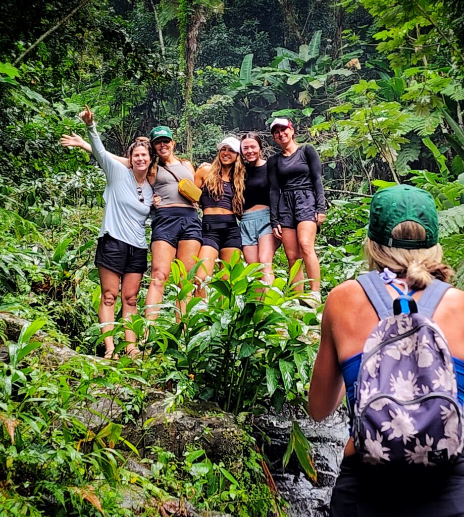 A lively bachelorette party visiting Puerto Rico and staying at St Regis Bahia Beach takes a moment to pose amid the vibrant foliage on the trail to Las Delicias Waterfall in Toro Negro Rainforest. This adventure is part of Bucketlist Tours’ Tropical Rainforest Magic & Wonders, and the exclusive Discover Puerto Rico 3-Day Package Private Experiences showcasing the island's natural beauty and tranquility.