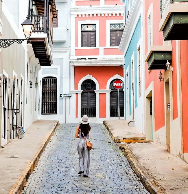 A solo traveler and passenger of Ritz Carlton's Cruise EVRIMA, explores the vibrant streets of Old San Juan, Puerto Rico, as part of Bucketlist Tours’ Ageless Elegance, Heritage, and Spirits, and the exclusive Discover Puerto Rico 3-Day Package Private Experiences." Captured by her guide, this enchanting moment showcases the beauty of the city's colonial architecture and iconic cobblestone paths.