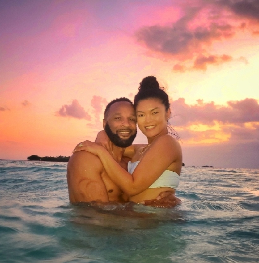 A joyful couple traveling to Puerto Rico, staying at the luxurious St. Regis Bahia Beach, shares a tender embrace during a spectacular Caribbean sunset. This unforgettable moment was captured by their guide and Bucketlist Tours Ambassador, highlighting the serene and intimate experiences offered as part of the Mystic Waters under the Sun & Stars and Discover Puerto Rico 3-Day Package Private Door to Door Experiences.