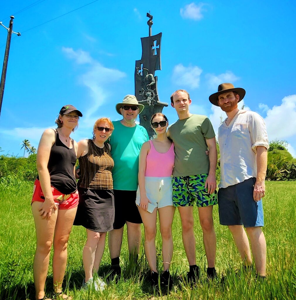 A multigenerational family from Manhattan, including seniors, stands happily alongside their guide and ambassador in front of the majestic Birth of a New World statue, America's tallest monument, under a brilliant sunny sky. Staying at the renowned Caribe Hilton, the family enjoyed this enriching stop as part of Bucketlist Tours' Perfect Beach Escapade: Northern Coastal Adventure, a highlight of their Discover Puerto Rico 3-Day Package Private Experience.