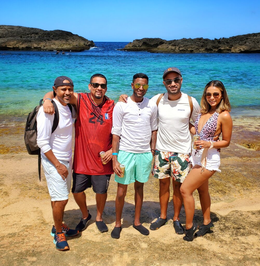 A vibrant group of young Wall Street professionals smiles for a photo with their guide and ambassador at the pristine Mar Chiquita Beach in Puerto Rico. Staying at The Ritz-Carlton Reserve at Dorado Beach, they bask in the beauty of a perfect sunny day during Bucketlist Tours' Perfect Beach Escapade: Northern Coastal Adventure, an extension of their Discover Puerto Rico 3-Day Package Private Experience.