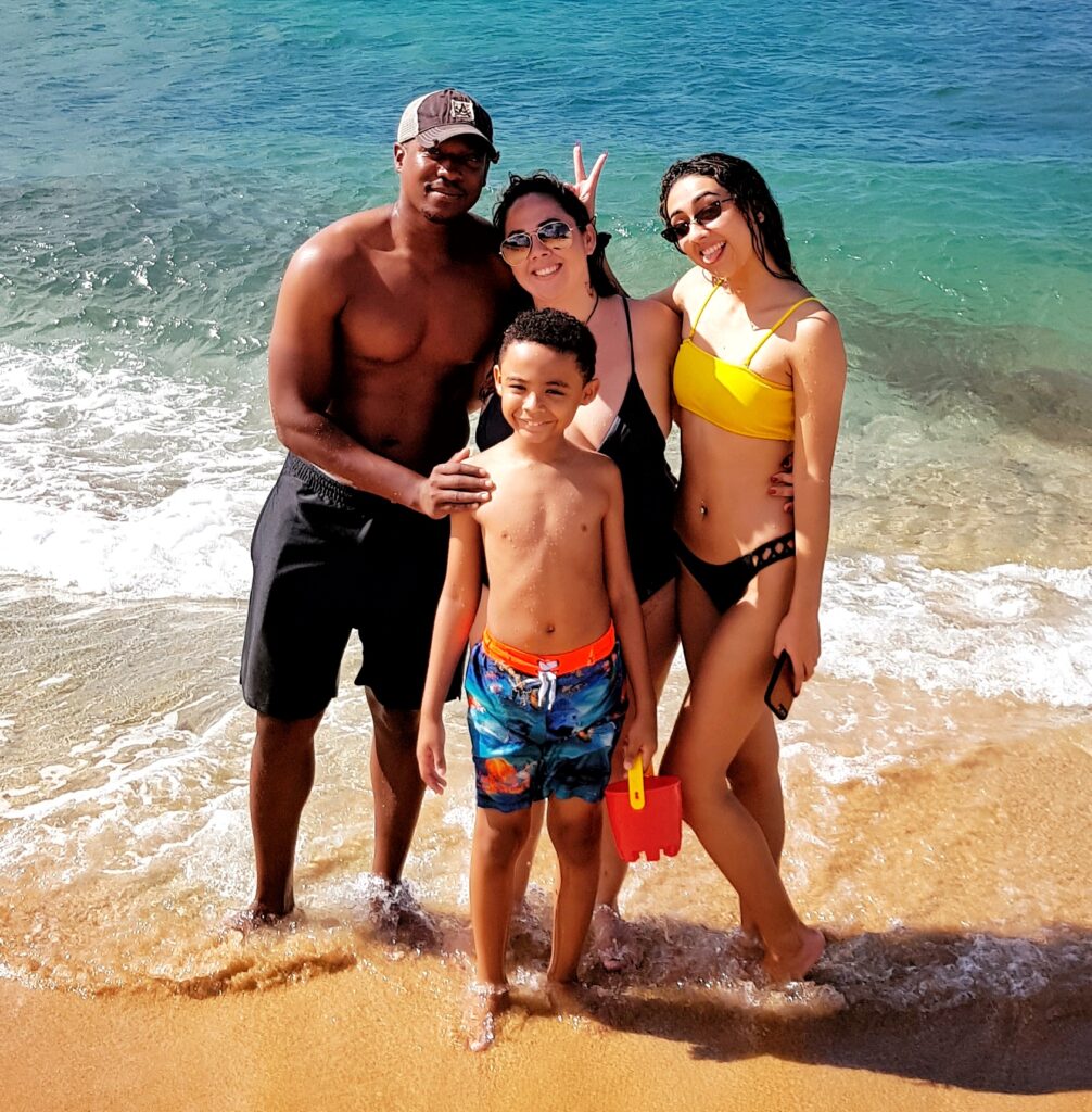 A joyful family of four with children poses for a photo at the stunning Mar Chiquita Beach in Puerto Rico, their smiles reflecting the perfect sunny day. Staying at the luxurious St. Regis Bahia Beach, they explored this hidden gem as part of Bucketlist Tours' Perfect Beach Escapade: Northern Coastal Adventure Private Experience.