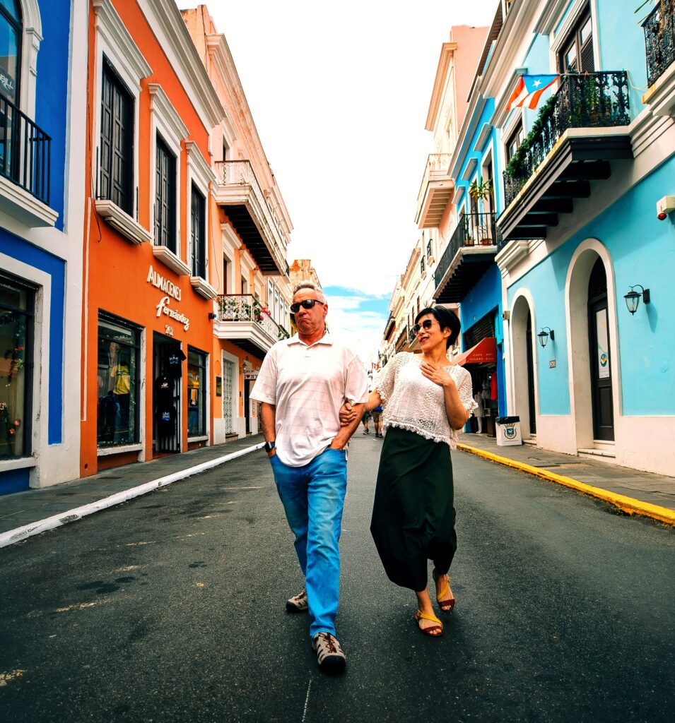 A senior couple traveling to Puerto Rico, staying at the *Fairmont El San Juan*, is captured by their guide and ambassador while leisurely strolling along the *cobblestone streets* of *Old San Juan*. Surrounded by colorful colonial architecture, they delve into the rich colonial history of Puerto Rico, learning how the island has flourished since becoming a Commonwealth of the United States. This moment is part of their Old San Juan's Whispers of Time private tour, the most informative and history-packed exploration of the area. This tour encompasses over 90 landmarks on the San Juan islet, including the Capitol Building, the *Walkway of the Presidents* (honoring all U.S. presidents who have visited the island), the North Wall, and the main streets of the old city. The tour is the perfect *shoreline excursion* for cruiseship passengers and offers three customizable durations: a 2-hour comfortable sightseeing option in a luxury air-conditioned vehicle, a 3-hour tour with 2–3 photo stops for in-depth exploration, and a 4-hour tour allowing for 4 extended stops. These *Old San Juan tours* are thoughtfully curated with safety and comfort in mind, making them ideal for couples, families with children, seniors, and individuals seeking minimal effort with maximum enrichment or those with mobility constraints.