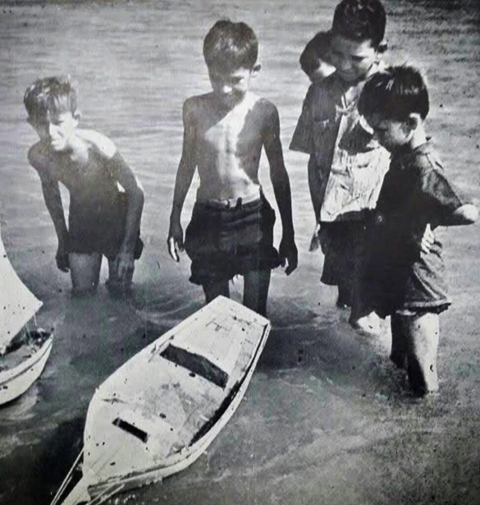 Bucketlist Tours Co-Founder Carlos Alexis, also known as Papito, as a child, playing with handmade boats crafted from discarded wood leftover from his grandfather’s carpentry projects. Growing up poor in the Puerto Rican countryside, Carlos dreamed of sailing away to create a place where he could make others’ dreams a reality—something he had longed for but never experienced. This image captures a moment of youthful imagination that would inspire a lifetime of ambition. Forty-five years later, Carlos and his son, Marcos Alexis, co-founders of Bucketlist Tours, are living that dream, transforming their passion into a reality by creating unique experiences that fulfill visitors’ dreams, one journey at a time.